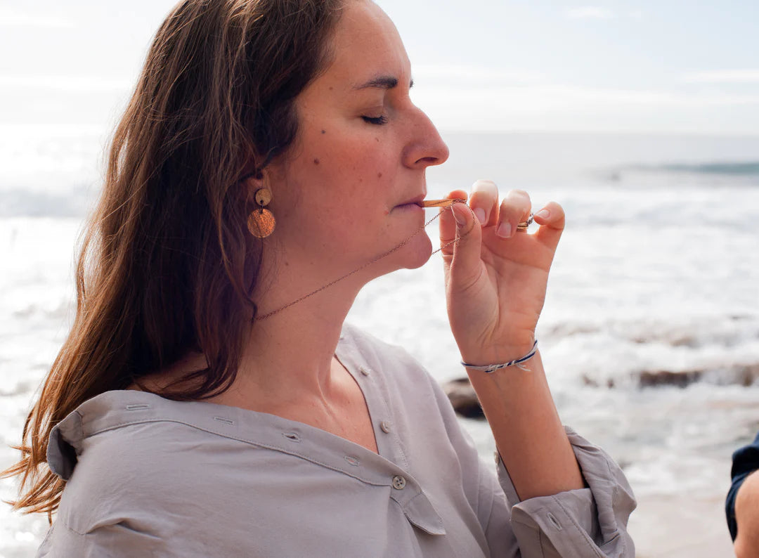 Woman near the sea doing mindful breathing using Breathe Into Peace Mindful Necklace