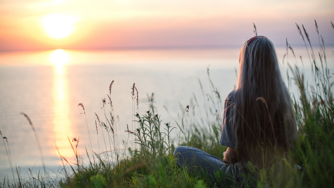 Sitting woman infront of the river watching the sunset