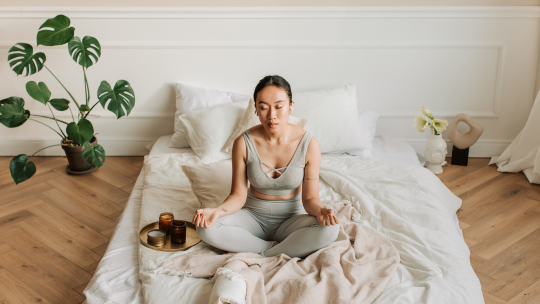 Woman in exercise clothes sitting in bed doing mindful breathing to relieve anxiety attack