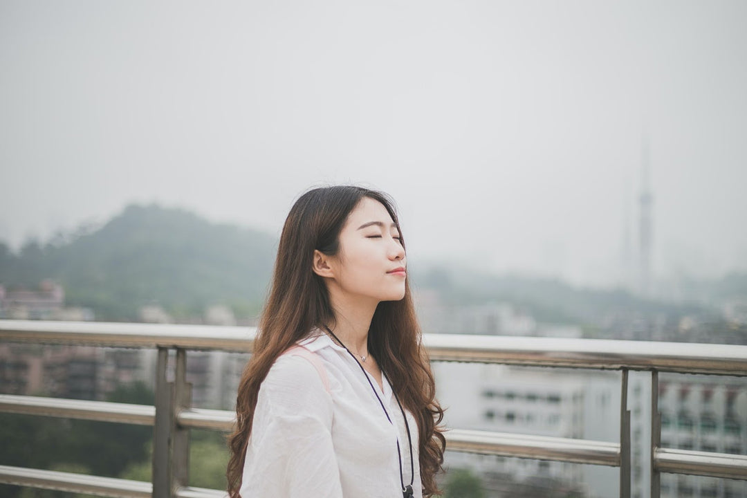 Woman doing mindful breathing techniques outside the top of a building with amazing city view