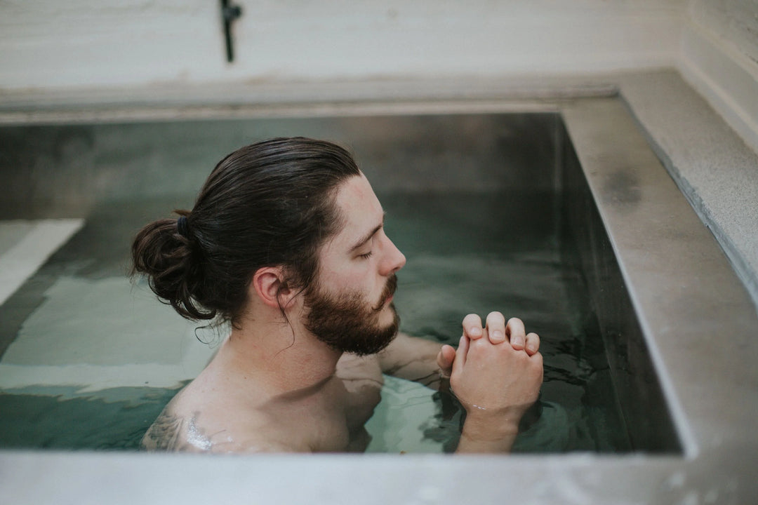 Man in hair bun style and thick mustache dipping in water pool doing mindful breathing exercises